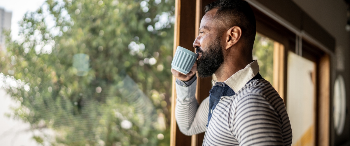 May 22 blog Man sipping coffee and looking out window.